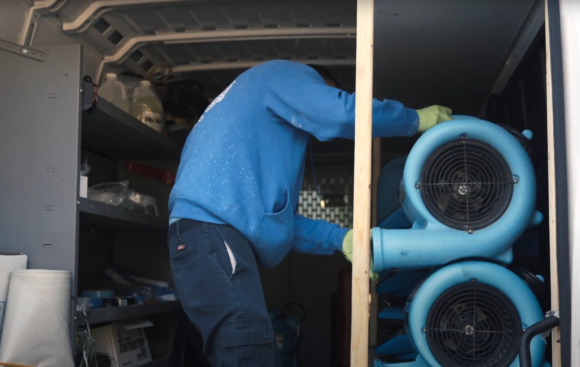 Water damage restoration technician working with industrial drying fans and equipment
